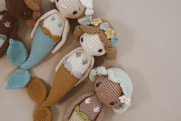 Several crocheted amigurumi mermaid dolls with pastel tails, floral accents and embroidered details