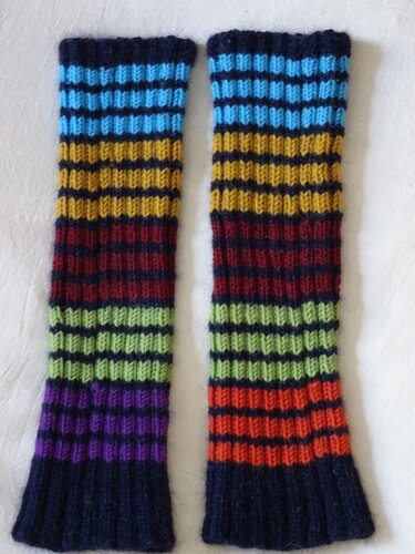 Paar gestrickter Beinstulpen mit bunten Querstreifen auf hellem Hintergrund