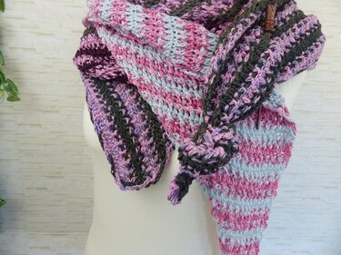 Gehäkeltes mehrfarbiges Dreieckstuch in Pink, Hellblau, Lila und Anthrazit, mit hölzerner Brosche an einer Schaufensterpuppe