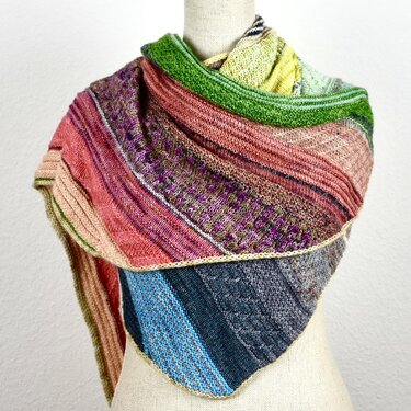 Mehrfarbiges gestricktes Dreieckstuch auf Schneiderpuppe mit Streifen und Strukturmustern