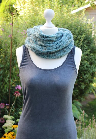Schaufensterpuppe mit blau-grün meliertem gestricktem Loop-Schal über grauem Top