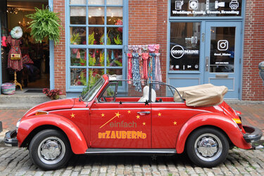 Rotes Cabriolet mit Sternen und Schriftzug „einfach bezaubernd“ auf Kopfsteinpflaster