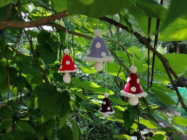 Kleine schnell gehäkelte Pilzanhänger in Rot, Dunkellila und Helllila mit weißen Punkten an Schnüren