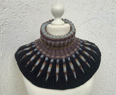 Schwarzer gestrickter Kragenschal mit hohem geripptem Rollkragen und schmalen mehrfarbigen Streifen, präsentiert an einer Schaufensterpuppe.
