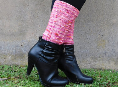 Rosa gestrickte Beinstulpen mit Zopfmuster an schwarzen Stiefeletten
