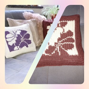 Zwei gehäkelte Kissenbezüge mit Blumenmotiv (Lila‑Weiß und Braun‑Weiß) auf grauem Sofa