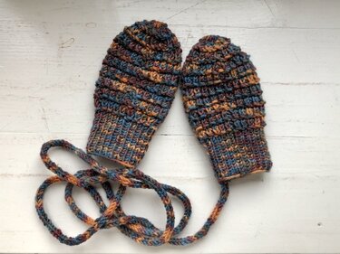 Gestrickte Baby-Fäustlinge in meliertem Blau, Braun und Orange, verbunden durch ein geflochtenes Band