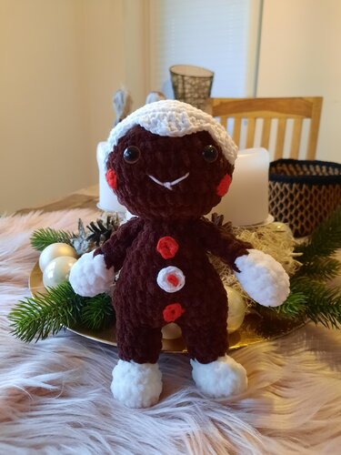 Gehäkelter Lebkuchenmann Amigurumi in Braun mit weißen Zuckerguss-Akzenten und roten Knöpfen
