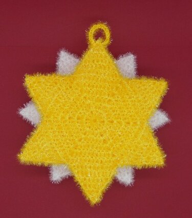 Yellow six-pointed crochet star ornament with white textured backing layer and hanging loop on a red background.