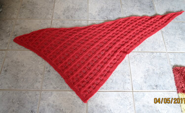 Korallrotes gestricktes Dreieckstuch mit diagonalen Ajourstreifen auf hellen Fliesen