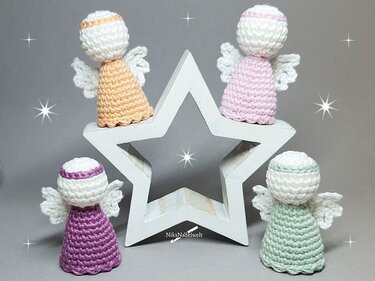 Vier schnell gehäkelte Mini-Engel in Pastell vor weißem Holzstern