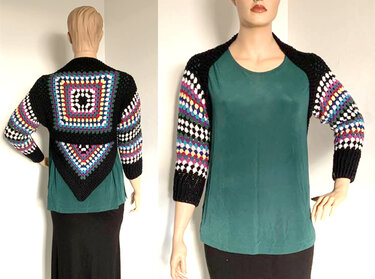 Gehäkelter schwarzer Bolero mit bunten Granny Squares an Rücken und Ärmeln auf einer Schaufensterpuppe.