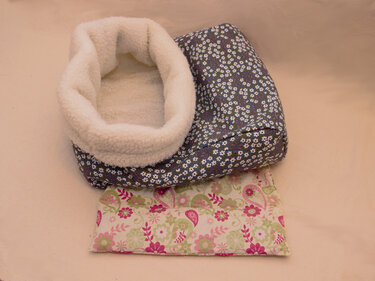 Gefütterter Kuschelsack mit cremeweißem Fleece und dunkelblauem Außenstoff mit kleinen weißen Blumen; flaches Kissen mit rosa-grünem Blumen- und Paisley‑Muster