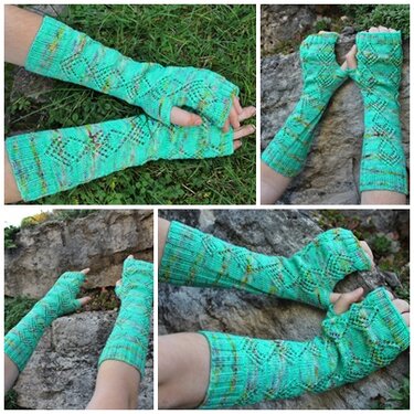 Paar lange, minzgrüne, fingerlose Strick-Armstulpen mit Rauten‑Lochmuster und Daumenöffnung auf Gras und Felsen