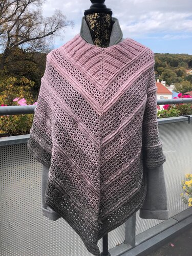 Gehäkelter Damenponcho in Rosa und Grau mit Ombré-Farbverlauf und V-Form auf einem Mannequin im Freien