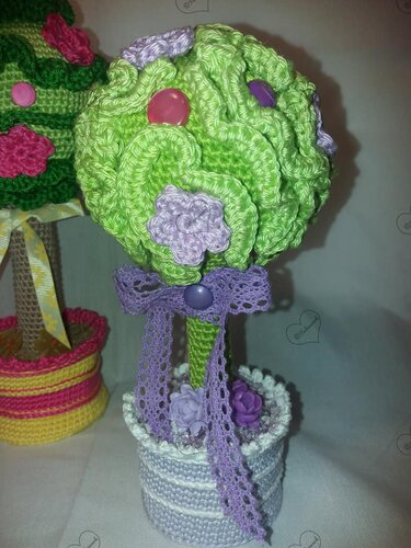 Gehäkeltes Topiary: grüne Kugel mit lila Blüten, Spitzenband und gestreiftem Topf