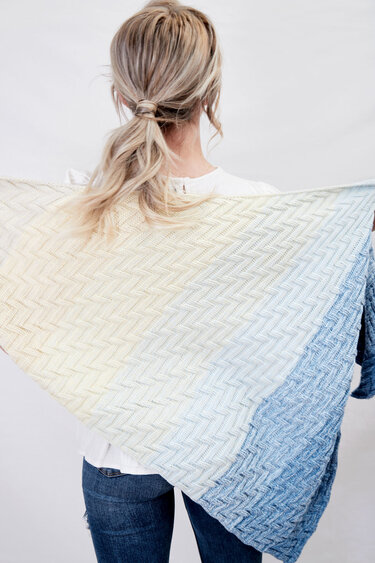 Rückansicht einer Person mit gestricktem Dreieckstuch (Creme bis Blau) und Zickzackmuster
