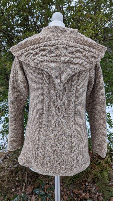 Detailaufnahme Rücken einer beigefarbenen Strickjacke mit zentralem Zopfmuster und breitem Kragen