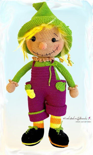 Gehäkelte Amigurumi-Vogelscheuche mit grünem Hut und lila Latzhose