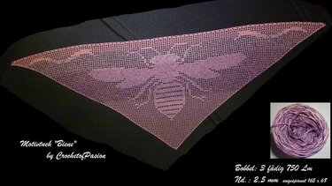 Dunkles Dreieckstuch, gehäkelt mit großem Bienenmotiv in Rosa‑Lila; daneben ein passendes Garnknäuel.
