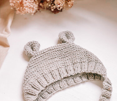 Gestrickte Baby-Öhrchen-Mütze in Grau, kraus rechts mit Rippenbündchen und Bindebändern