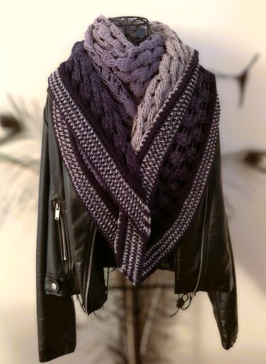 Triangle crochet shawl in dark purple and lavender gradient with textured and lacy panels, draped over a black jacket on a dress form