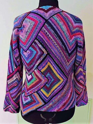 Rückenansicht eines bunten gestrickten Damenpullovers mit diagonal angeordneten Quadratmotiven auf einer Schneiderpuppe