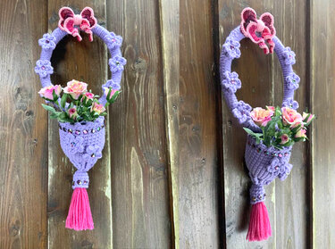 Gehäkelter lila Türkranz mit Körbchen voller rosa Rosen und pinker Quaste an einer Holzwand