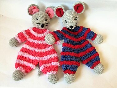 Zwei gehäkelte Mäuse in gestreiften Overalls (rosa/rot und blau/rot) auf weißem Hintergrund