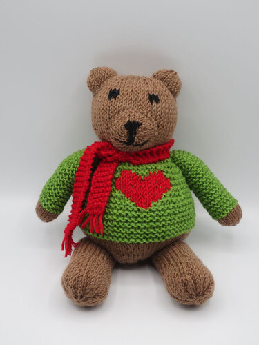 Brauner gestrickter Teddy mit rotem Schal und grünem Pullover mit rotem Herz
