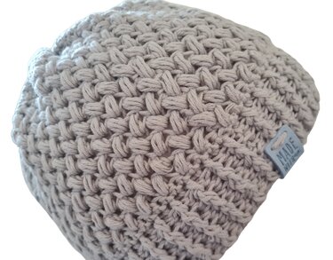 Hellgraue gehäkelte Beanie mit ausgeprägtem Strukturmuster und kleinem Etikett an der Seite.