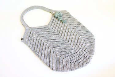 Flat-laid gray chevron crochet shoulder bag with integrated strap and tassel