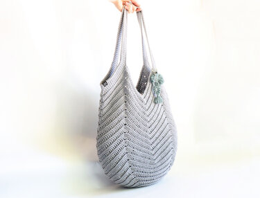 Light grey crochet shoulder bag with chevron stitch pattern and tassel charm