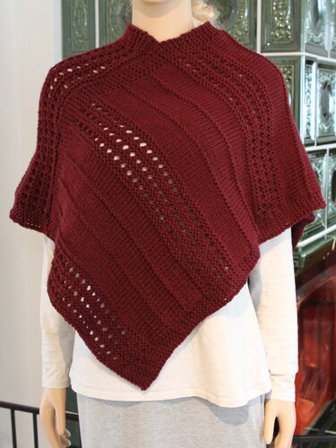 Dunkelroter gestrickter Poncho mit diagonalen Mustern und hohem Kragen auf Schaufensterpuppe