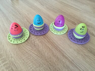 Vier gehäkelte Eierwärmer mit runden Untertassen in zwei Farben als DIY-Idee
