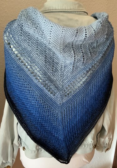 Nahaufnahme: tunesisch gehäkeltes Dreieckstuch mit Lochreihen und Farbverlauf, auf Jacke drapiert