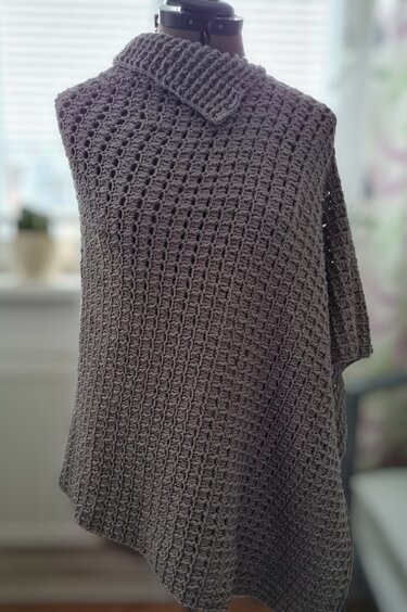 Grau gehäkelter Damenponcho mit breitem Rollkragen auf Schneiderpuppe