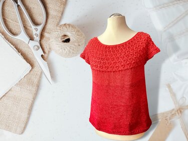 Rotes kurzärmeliges Strickshirt mit gemusterter Passe am Rundhalsausschnitt auf Schneiderpuppe.