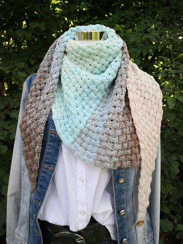 Gestricktes Dreieckstuch in Mint-, Blau- und Beigetönen mit wabenartiger Struktur auf Schaufensterpuppe mit Jeansjacke