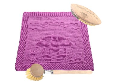 Lila gestricktes Spültuch mit Pilzmotiv, neben zwei Holzspülbürsten.