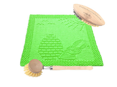 Grünes gestricktes Spültuch mit Osterei- und Blattmuster neben zwei Holzspülbürsten