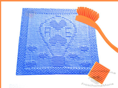 Blaues quadratisches Stricktuch mit Heißluftballon- und Wolkenmuster, daneben orangefarbene Bürste und Scheuerpad