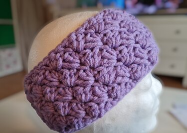 Fliederfarbenes gehäkeltes Stirnband mit Puffstich-Relief auf Schaufensterkopf