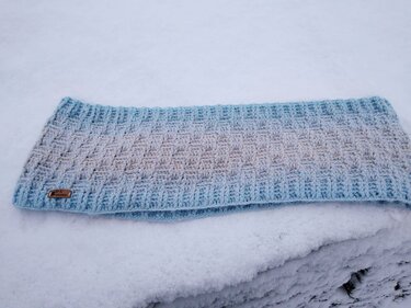 Gehäkelter Loopschal hellblau-beige mit Korbgeflechtmuster auf Schnee