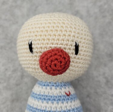 Gehäkelte Amigurumi-Puppe mit roter runder Nase und gestreiftem Körper