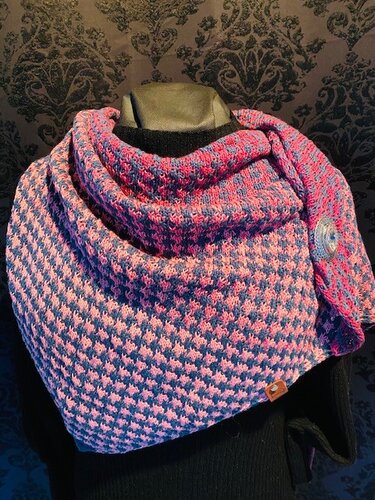 Gestricktes, zweifarbiges Dreieckstuch in Rosa und Blau mit feinem Muster und Zierknopf auf einer Schaufensterpuppe