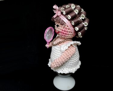 Gehäkelter Eierwärmer in Damenform mit Lockenwicklern, rosa Haarband und Handspiegel