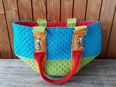 Turquoise and lime green crocheted tote with orange handles, silver clip hardware and red lining
