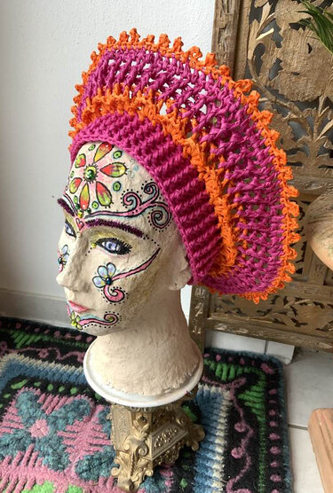 Bemalter Mannequinkopf mit pink-orange gehäkelter Baskenmütze und Rüschenrand