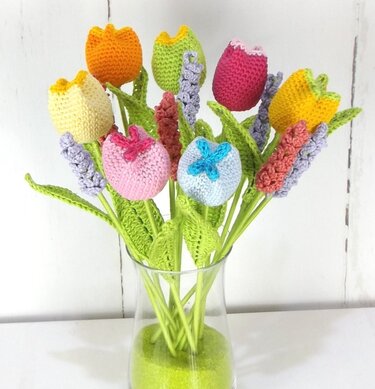 Gehäkelte bunte Tulpen und Hyazinthen in einer Glasvase